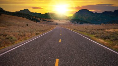 Long empty stretch of a two-lane highway heading toward a golden sunrise over a mountain pass on the horizon. Conceptual for freedom, enjoying the journey, and the promise of a new day. clipart