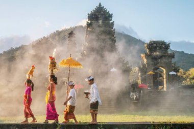 Ubud, Bali - 30 Temmuz 2016. Bir anne ve çocuk geleneksel Bali törenleri kıyafetleri içinde ve dini hediyeler taşıyarak Hindu tapınağına yürür..