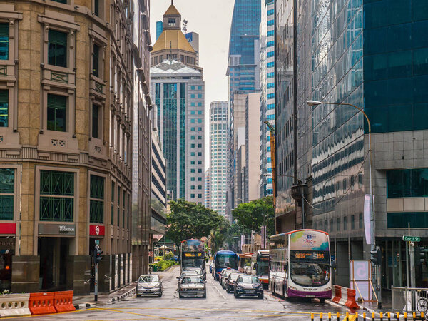 Singapore, Singapore - December 6, 2015. Traffic stopped at a red light on Robinson Road in Singapore's downtown business core, surrounded by skyscrapers on both sides.