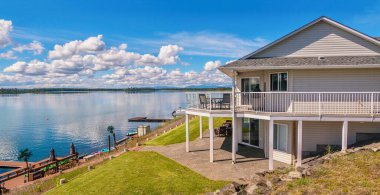 Geniş açılı güzel, büyük, modern, lüks bir yazlık ev manzarası, güneş güverteleri, cam korkuluklar ve geniş pencereler, Kanada 'nın orta kesimindeki British Columbia' da küçük bir gölün yanında geçiyor..