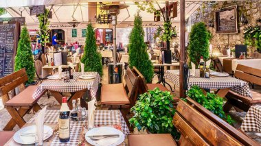 Kotor, Karadağ - 5 Haziran 2016. Yabancı turistlere hizmet veren bir açık hava restoranının masa takımı ve öğle yemeği için bir menü tahtası var..