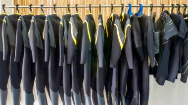 Filipinler 'deki bir tatil köyü dalış mağazasında askıda asılı bir sıra neoprene dalış kıyafeti..