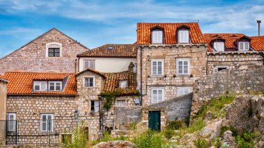 Hırvatistan 'ın Dubrovnik kentindeki pencereleri kepenkli ve turuncu kiremitli çatıları olan geleneksel taş evler. Bazıları iyi bakılmış, bazıları harap olmuş..