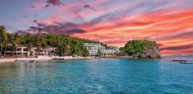 Puerto Galera, Philippines - June 4, 2021. Hotels and dive resorts on the waterfront of Small Lalaguna Beach in the Sabang area of the popular resort destination on Mindoro Island. clipart