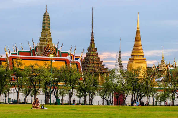 Orang-orang duduk di Sanam Luang di depan Wat Phra Kaew dan Istana Agung Stok Gambar