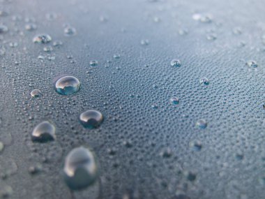 Mavi arka planda cam üzerine su damlaları