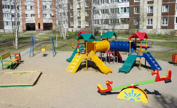 Yüksek binaların bahçesindeki oyun bahçesinde kaydırak ve merdivenlerle renkli plastik çocuk kasabası