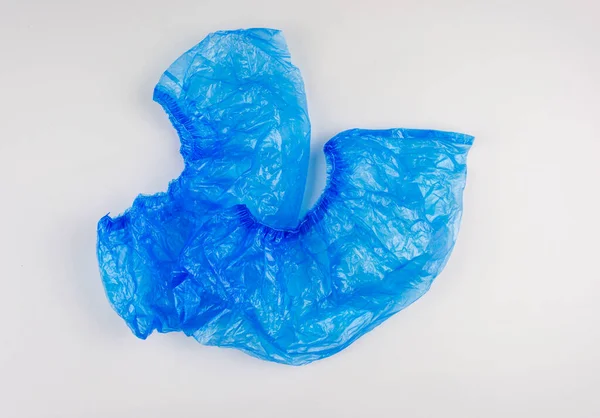 Tıbbi mavi plastik ayakkabı kılıfları beyaz arka planda yalıtılmış. Bir çift galoş. Tıp kurumlarında hijyen, güvenlik ve temizlik