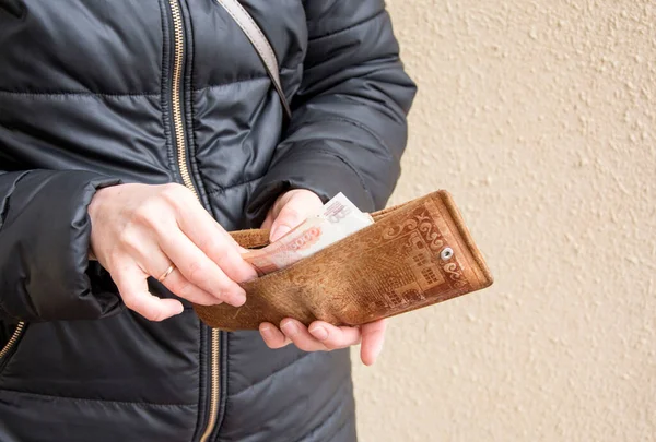 women's hands take money out of a leather wallet. They put money in their wallet