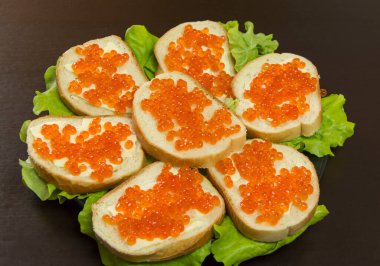 Kırmızı havyarlı lezzetli sandviç, tereyağı ve tabakta taze marul yaprakları.