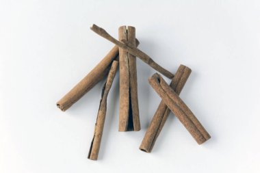 Beyaz arka planda birkaç tarçın çubuğu dikkatsizce uzanır.