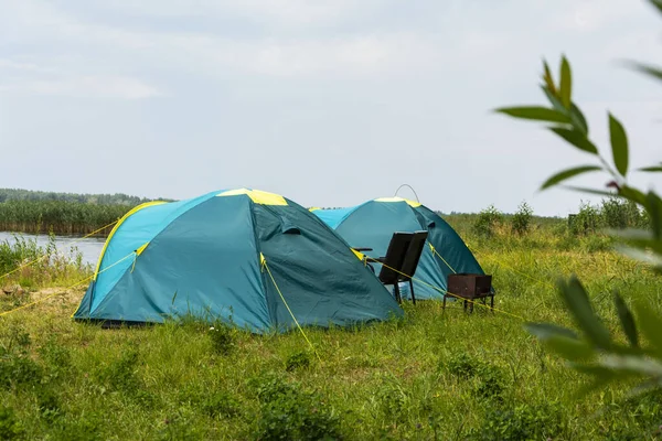 Göl kıyısında kamp yapmak için turist çadırları, seyahat geçmişi. Balıkçılık, turizm, aktif eğlence. Doğa manzarası. Yaşam tarzı tasarımı için. Açık hava eğlencesi.