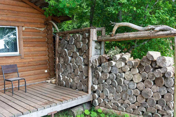 Sauna sobası için yakacak odun, saunalar ahşap kırsal banyonun yanına istiflenmiş. Yaşam tarzı tasarımı için. Duvarda bir sıra yakacak odun var. Kırsal alan.