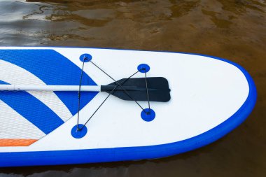 SUP tahtası, yakın plan suyun arka planında kürek olan kürek tahtası. SUP biniş ekipmanları. Açık havada su sporları. Sörfçülerin yaşam tarzı.