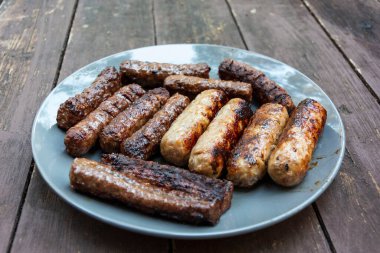 Tabakta ızgara sosis. Ahşap bir arka planda. Şişko sosisler..