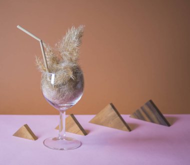 Pampas otlu kokteyli bir bardakta pampa sapından yapılmış pipetle. Minimum soyut kompozisyon arka planı. Japon iç mimari fikri. Serinletici fikir. Seçici odaklı iki renk arkaplanı.