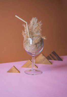 Pampas otlu kokteyli bir bardakta pampa sapından yapılmış pipetle. Minimum soyut kompozisyon arka planı. Japon iç mimari fikri. Serinletici fikir. Seçici odaklı iki renk arkaplanı.