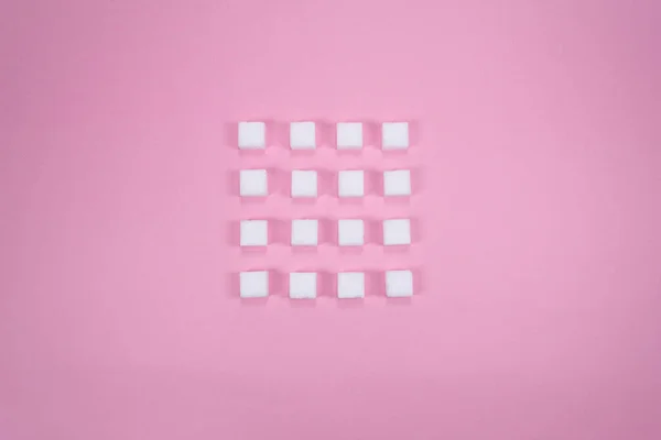 Beyaz şeker küpleri pembe arka plan kompozisyonu. Minimum gıda konsepti. Sağlıksız yaşam tarzı fikri.