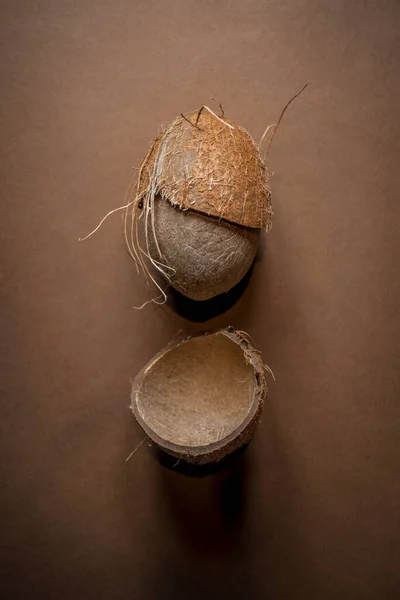 Semi cracked coconut on sandy brown background. Minimal tropical fruits concept. Summer vibes idea. Difficult task idea.