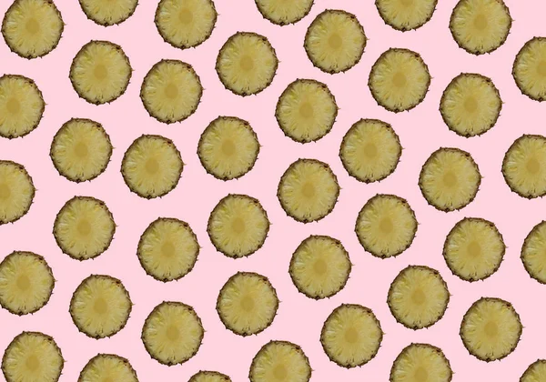 Rastgele yerleştirilmiş ananas dilimleri modayı takip eden pembe arka planda çoğalıyor. Asgari yaz konsepti.