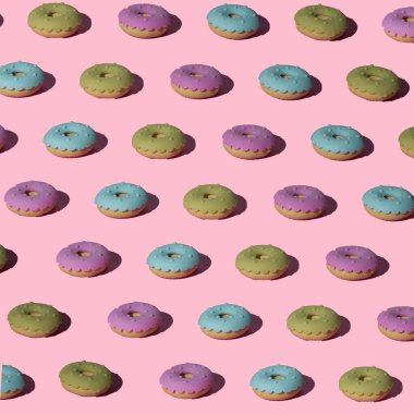 Moda pastel pembe arka planda yeşil, mavi ve pembe çörekler. Kusursuz desen. Üst Manzara. En az yiyecek ve yaz konsepti.