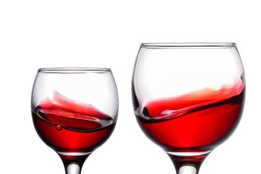 Beyaz arka plan nesnelerinin üzerinde kırmızı şarap bulunan iki şeffaf bardağın büyüleyici patlamaları üzümlerden alınan alkollü içecek tasarımı konsepti için.