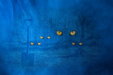 Kürek, gece ormanının arka planında yere saplanır. Vahşi hayvanların parlak gözleriyle. Gizemli doğa kavramı.