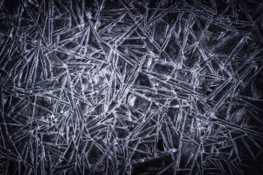 Kışın karanlık arka planında çatlakları olan parlak ve ilginç buz dokusu.