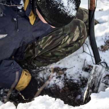 Adam çukurda bir şey arıyormuş. Bir eliyle başını eğmiş, yeri kazmış ve diğer eliyle de bir kazı küreği tutmuş.