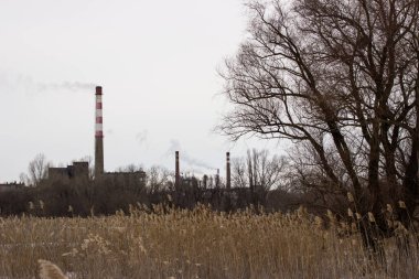 Dumanı şehrin kenar mahallelerinde bulunan bir boru fabrikasının şehir manzarası çevre kirliliği kavramı.