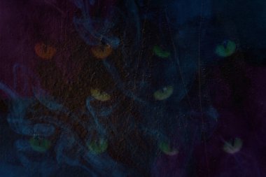 Paslı metalin arka planında mavi şeffaf, tehditkar gözler. Gizemli soyutlama.