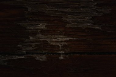 Koyu, gizemli ahşap doku ve çatlak yakın plan. Kısmen yırtık yüzey. Tasarım için gizemli atmosfer arkaplanı.
