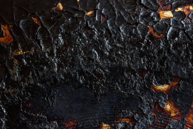Kızartma tavasının yüzeyinde yanmış ve çatlamış metalin siyah dokusu tasarım için heyecan verici yakın plan grunge arkaplanı
