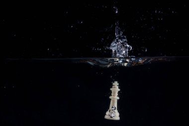 Suya düşen beyaz satranç kralı karanlık bir zeminde güzel bir sıçrama oluşturdu.