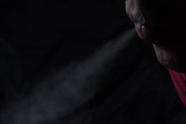 Çerçevenin üst köşesinde sigara içen adamın dudakları kötü alışkanlık kavramını ortaya çıkaran ince bir gri duman seli yaydı.