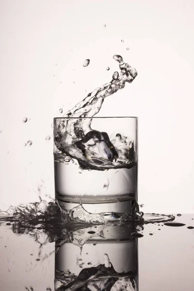 Köstliche Wasserspritzer Einem Glas Aus Fallendem Eis Auf Grauem Hintergrund — Stockfoto