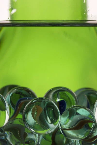 Dekorative Glaskugeln Einem Glas Mit Flüssiger Nahaufnahme Auf Hellgrünem Hintergrund — Stockfoto