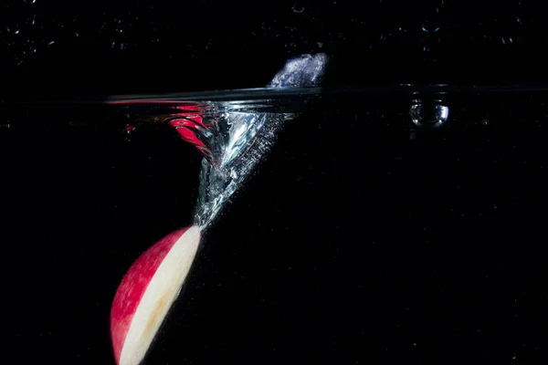 Ekscytujący Rozprysk Wody Przekątnej Upadłego Kawałka Jabłka Czerwoną Skórką Koncepcji — Zdjęcie stockowe