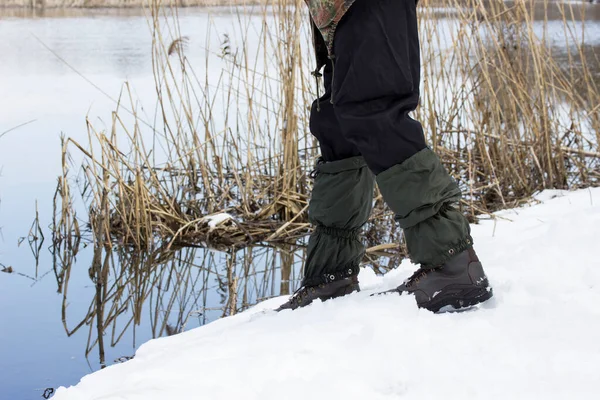 暖かい靴を着た漁師が川の近くに立って釣りの概念を — ストック写真