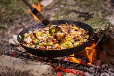 Kızarmış domuz yağı ve sebzeler açık hava yeme ve yürüyüş kavramında ateşte.