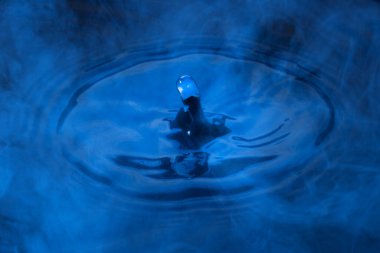 Suyun üzerindeki gizemli mavi buhar doğal elementlerin soyut ve heyecan verici bir damlası.