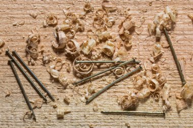 Metal ince çiviler, sanayi ve ahşap işçiliği konseptinde ahşap talaşı ile yatar.