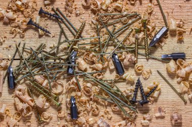 Bir tornavida için altın ve siyah vidalar gümüş çiviler ve nozüller iyi ahşap parçaları ile iş yerinde yatıyor araçlar ve ahşap konsepti