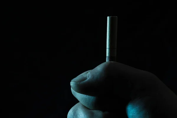 在与吸烟和反社会习惯作斗争的黑暗背景下手压香烟 — 图库照片