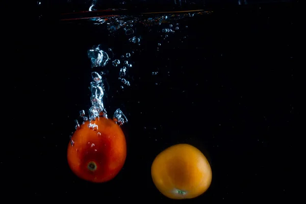 Dwa Jasne Pomidory Spadają Dno Ciemnej Wodzie Pozostawiając Piękny Szlak — Zdjęcie stockowe