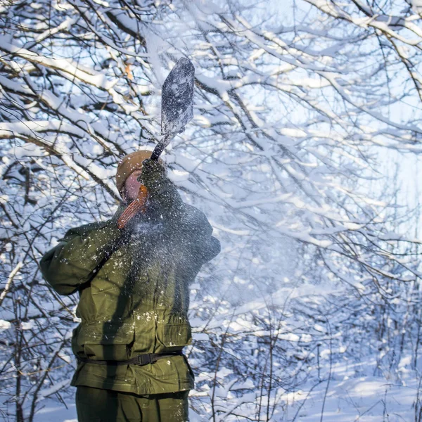 拿着一把蓝宝石铲子的人被暴风雪覆盖着 背景模糊不清 白雪覆盖着树木 — 图库照片