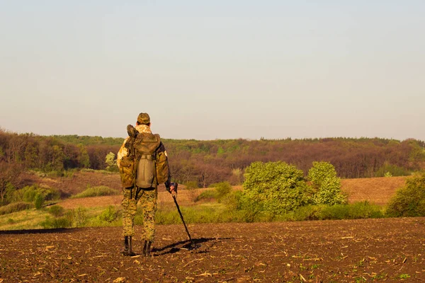 金属探知機を持った男が野外活動という緑の森の概念の地平線を見ている — ストック写真