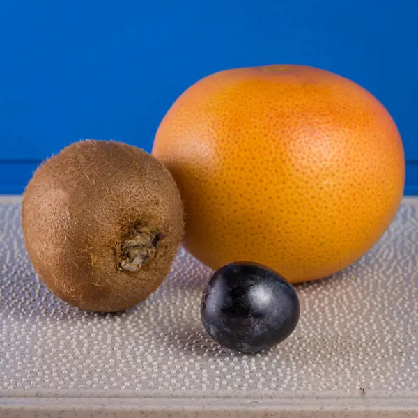 Three Sweet Healthy Fruits Plastic Kitchen Board Pimples Blue Background — Stock Photo, Image