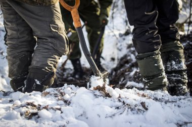 İstihkamcı küreği ve üç çift ayak kış ormanında bir deliğin üzerinde duruyor.