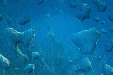 Mavi metal yüzeyine güzel su damlaları ve tasarım için yakın plan çizikleri.